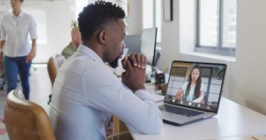 Çift ırklı iş arkadaşlarıyla görüntülü konuşma için bilgisayarını kullanan Afro-Amerikalı iş adamı. ticari iletişim teknolojisi, dijital kompozit video.