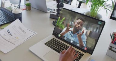 Afrikalı Amerikalı iş arkadaşı ile video görüşmesi için bilgisayarını kullanan Afro-Amerikalı bir iş kadını. ticari iletişim teknolojisi, dijital kompozit video.
