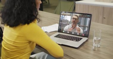 Afrikalı Amerikalı bir kadının beyaz bir erkek arkadaşla laptopta görüntülü konuşma yaptığı video. iş, işbirliği ve ofiste dijital olarak üretilen teknoloji konseptiyle çalışmak.