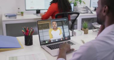 Afrikalı Amerikalı bir adamın çift ırklı bir kadın çalışanla bilgisayarında görüntülü konuşma yaptığı video. iş, işbirliği ve ofiste dijital olarak üretilen teknoloji konseptiyle çalışmak.