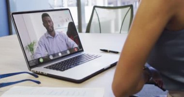 Afro-Amerikalı bir kadının, Afrikalı Amerikalı erkek bir iş arkadaşıyla laptopta görüntülü konuşma yaptığı bir video. iş, işbirliği ve ofiste dijital olarak üretilen teknoloji konseptiyle çalışmak.