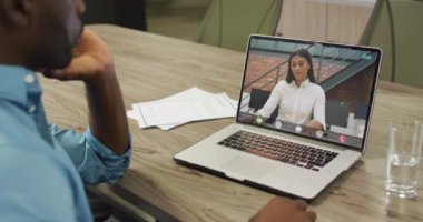 Afrikalı Amerikalı bir adamın çift ırklı bir kadın çalışanla bilgisayarında görüntülü konuşma yaptığı video. iş, işbirliği ve ofiste dijital olarak üretilen teknoloji konseptiyle çalışmak.