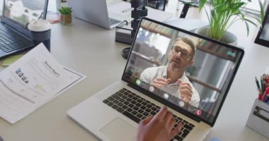 Çift ırklı bir kadının beyaz erkek iş arkadaşıyla bilgisayarında görüntülü konuşma yaptığı bir video. iş, işbirliği ve ofiste dijital olarak üretilen teknoloji konseptiyle çalışmak.