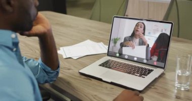 Afro-Amerikan bir adamın beyaz kadın bir iş arkadaşıyla laptopta görüntülü konuşma yaptığı video. iş, işbirliği ve ofiste dijital olarak üretilen teknoloji konseptiyle çalışmak.