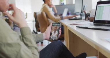 Kafkasyalı iş kadını Afro-Amerikan iş arkadaşı ile video görüşmesi için akıllı telefon kullanıyor. ticari iletişim teknolojisi ve dijital kompozit video.