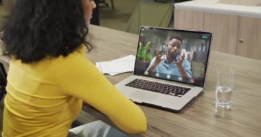 Çift ırklı iş kadını, Afrikalı Amerikalı iş arkadaşıyla görüntülü konuşma yapmak için dizüstü bilgisayar kullanıyor. ticari iletişim teknolojisi ve dijital kompozit video.