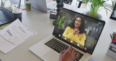 Çift ırklı iş arkadaşlarıyla video görüşmesi için bilgisayarını kullanan Afrikalı Amerikalı bir iş kadını. ticari iletişim teknolojisi ve dijital kompozit video.