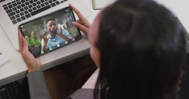 Afrika kökenli Amerikalı iş arkadaşıyla video görüşmesi için tablet kullanan iki ırklı bir iş kadını. ticari iletişim teknolojisi ve dijital kompozit video.