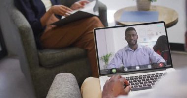 Afrikalı Amerikalı iş arkadaşlarıyla video görüşmesi için bilgisayarını kullanan Afro-Amerikalı iş adamı. ticari iletişim teknolojisi ve dijital kompozit video.