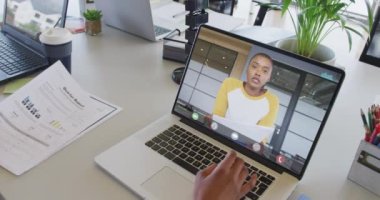 Afrikalı Amerikalı iş arkadaşı ile video görüşmesi için bilgisayarını kullanan Afro-Amerikalı bir iş kadını. ticari iletişim teknolojisi ve dijital kompozit video.