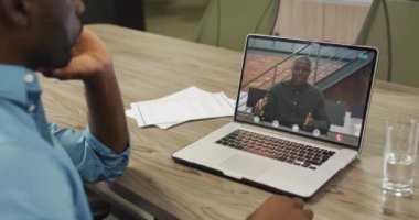 Afrikalı Amerikalı iş arkadaşlarıyla video görüşmesi için bilgisayarını kullanan Afro-Amerikalı iş adamı. ticari iletişim teknolojisi ve dijital kompozit video.