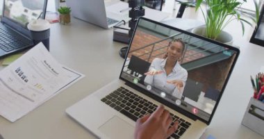 Afrikalı Amerikalı iş arkadaşı ile video görüşmesi için bilgisayarını kullanan Afro-Amerikalı bir iş kadını. ticari iletişim teknolojisi ve dijital kompozit video.