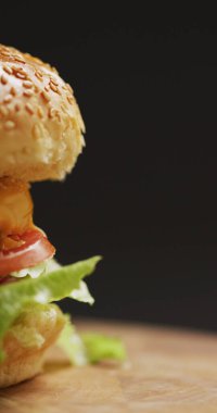 Gri arka planda salatalı taze ev yapımı hamburgerin dikey görüntüsü. Taze ev yapımı fast food..