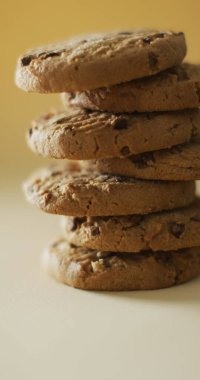 Sarı arkaplandaki çikolata parçalı kurabiyelerin dikey görüntüsü. tatlı yiyecekler ve şeker.