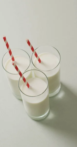Vertical Image Three Glasses Milk Red White Straw Grey Background — Stock Photo, Image