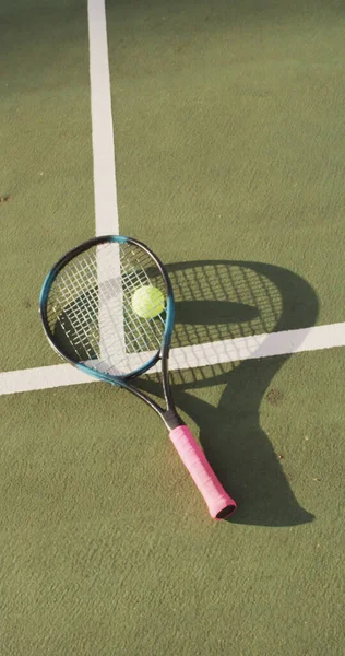 テニスコート上の黄色のテニスボールとラケットの垂直画像 健康的で積極的な退職 — ストック写真