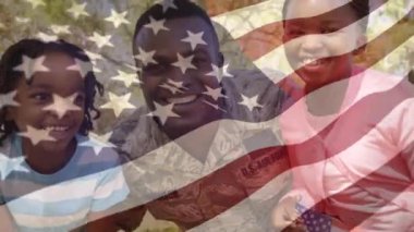 Animation of flag of america over happy african american soldier father embracing son and daughter. patriotism, family and celebration concept digitally generated video.