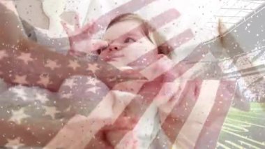 Stadyumun üzerinde sallanan Amerikan bayrağının animasyonu ve bebekle oynayan beyaz bir annenin elleri. aile, ebeveynlik, birliktelik ve vatanseverlik dijital olarak üretilen video konsepti.