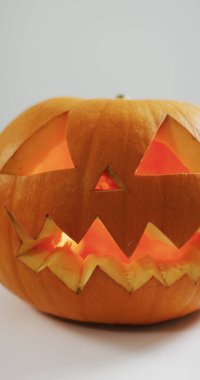 Beyaz arka planda oyulmuş Cadılar Bayramı kabağının dikey görüntüsü. Cadılar Bayramı, gelenek ve kutlama konsepti.