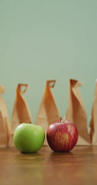 Pionowy Obraz Czerwonego Zielonego Jabłka Rzędem Zapakowanych Obiadów Papierowe Torby — Zdjęcie stockowe