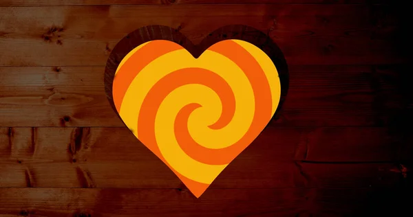 Image of rotating orange spiral background over heart shapes hole in brown wooden surface. shape, colour, movement, emotions and love concept digitally generated image.