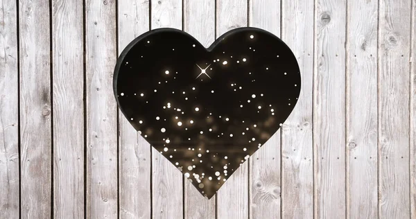 Image of starry background over heart shapes hole in grey wooden surface. shape, colour, movement, emotions and love concept digitally generated image.