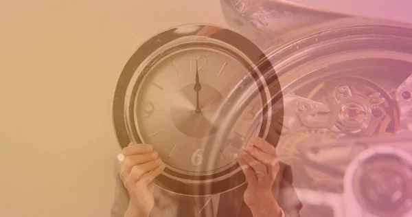 Image of clock over hands holding clock. global business and digital interface concept digitally generated image.