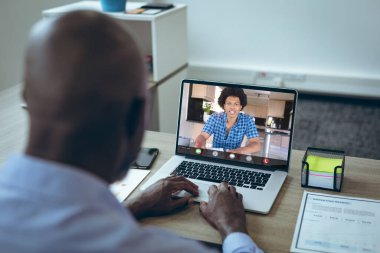 Afrika kökenli Amerikalı genç iş adamları bilgisayar konferansı sırasında ofisteki masada konuşuyor. değiştirilmemiş iş, kablosuz teknoloji, çalışma, takım çalışması ve ofis konsepti.
