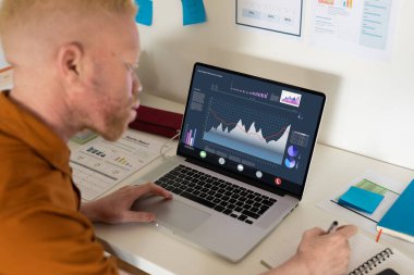 Afrika kökenli Amerikalı albino. Yetişkin iş adamı, ofiste dizüstü bilgisayarla çalışırken grafikle uğraşıyor. değiştirilmemiş, iş dünyası, kablosuz teknoloji, araştırma.