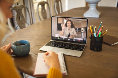 Gülümseyen Afro-Amerikan iş kadını çevrimiçi toplantı sırasında beyaz kadın meslektaşına el sallıyor. değiştirilmemiş, ofis, teknoloji, video konferansı, tartışma, internet, iş, takım çalışması.