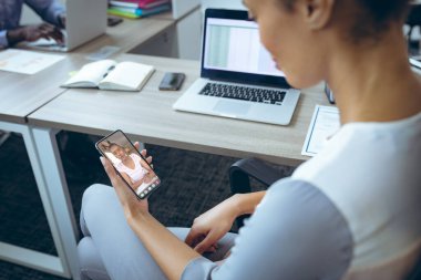 Afrika kökenli Amerikalı iş kadınları ofiste çalışırken telefon üzerinden video görüşmesi yapıyorlar. değiştirilmemiş, iş, kablosuz teknoloji, çalışma, toplantı, takım çalışması ve ofis konsepti.