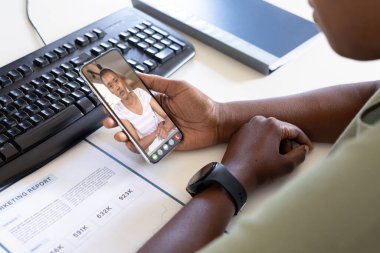 Afrikalı Amerikalı iş adamı Afrika kökenli Amerikalı bayan meslektaşıyla telefonda video konferansında. değiştirilmemiş, iş, teknoloji, çalışma, toplantı, takım çalışması ve ofis kavramı.