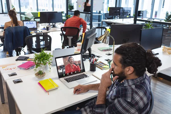 Çift ırklı iş adamı, çift ırklı erkek meslektaşıyla ofiste görüntülü görüşme yapıyor. değiştirilmemiş, iş, kablosuz teknoloji, video çağrısı, toplantı, çalışma, takım çalışması ve ofis konsepti.