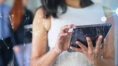 Tablet kullanan iki ırklı iş kadınının üzerindeki simgelerle bağlantı ağının animasyonu. Sosyal medya ve iletişim arayüzü kavramı dijital olarak oluşturulmuş video.