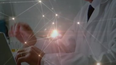 Animation of network of connections over caucasian senior male doctor using laptop. medicine, health, connections and technology concept digitally generated video.