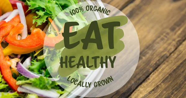 Image of eat healthy locally grown text in green, over bowl of fresh salad on wooden boards. vegan day, organic vegetable produce and healthy eating concept digitally generated image.