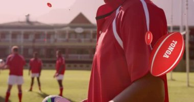 Animation of diverse male rugby player with rugby balls with tonga texts over stadium. global sport and rugby league world cup concept digitally generated video.