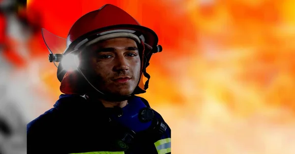 Caucasian firefighter wearing a helmet against spot of light and copy space on red background. safety concept