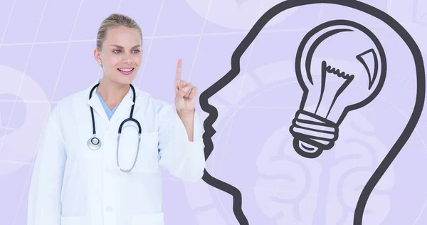 Composite of caucasian female doctor pointing and human head with light bulb on gray background. Smiling, world alzheimer\'s month, disease, healthcare, mental health, awareness and campaign concept.