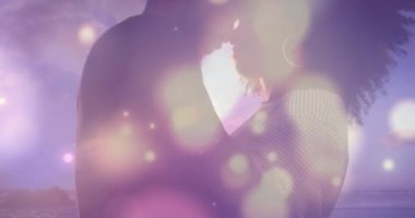 Afrika kökenli Amerikalı çiftlerin üzerinde parlayan mavi noktalar. Deniz kenarındaki kayalıklarda birbirlerini kucaklıyorlar. Aşk ve ilişki kavramı