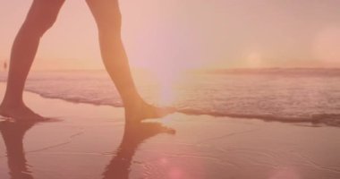 Sahilde yürüyen beyaz bir kadının bacaklarının üzerindeki ışıkların animasyonu. Etkin yaşam tarzı, spor, rahatlama ve deniz konsepti dijital olarak oluşturulmuş video.