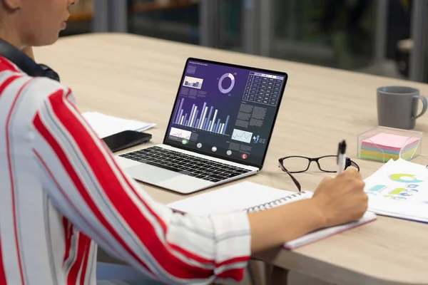 Ofiste dizüstü bilgisayardaki grafik verileri incelerken Asyalı iş kadınının rapor vermesinin orta kısmı. değiştirilmemiş, iş yeri, ofis, kablosuz teknoloji, internet.