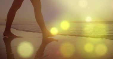 Sahilde yürüyen bir kadının orta kısmına karşı parlak sarı ışık lekeleri. Aşk ve ilişki kavramı