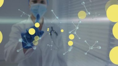 Kafkasyalı maske takan kadın doktorun üzerinde süzülen sarı noktaların animasyonu. Coronavirus covid 19 salgını sırasında dijital olarak üretilen ilaç, sağlık ve sağlık hizmetleri.