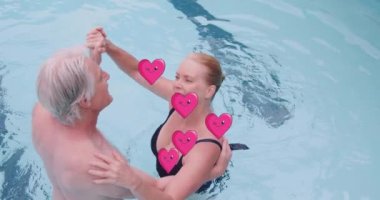 Animation of heart icons over caucasian senior couple dancing in pool. National dance day and digital interface concept digitally generated video.