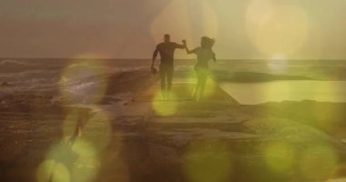 Afrika kökenli Amerikalı çiftlerin üzerinde sarı ışık lekeleri var. Deniz kenarındaki kayalarda el ele yürüyorlar. Aşk ve ilişki kavramı