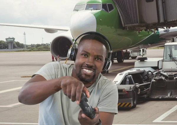 Composite image of african american man playing video games against airplane at the airport. games and aviation concept