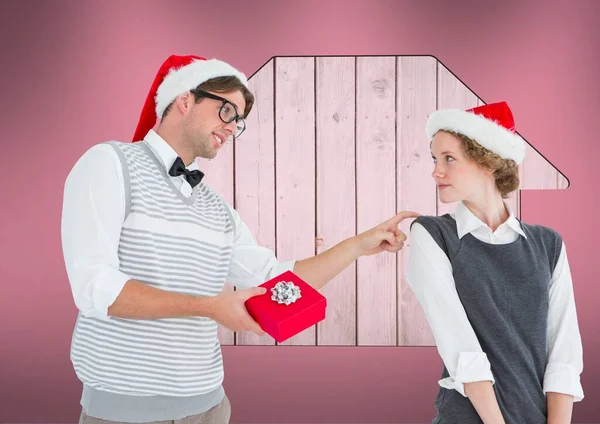 白人男性は ピンクの背景に家のアイコンとコピースペースを持つ妻にクリスマスプレゼントを与えています 不動産とクリスマスのコンセプト — ストック写真