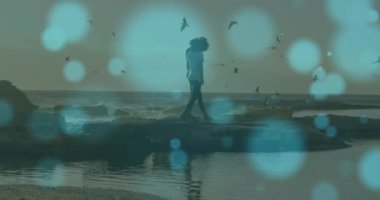 Denize yakın kayalıklarda yürüyen Afrikalı Amerikalı çifte karşı mavi ışık lekeleri. Aşk ve ilişki kavramı