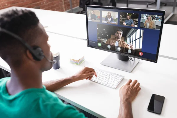 High angle view of african american businessman discussing online with colleagues over computer. video conference, unaltered, technology, teamwork, meeting, business, occupation and office concept.